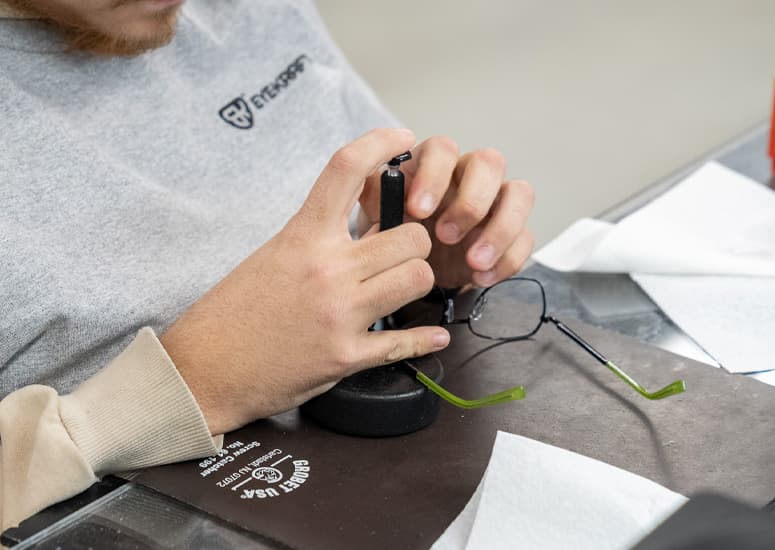 An EyeKraft technician at work on a pair of glasses at the finishing bench